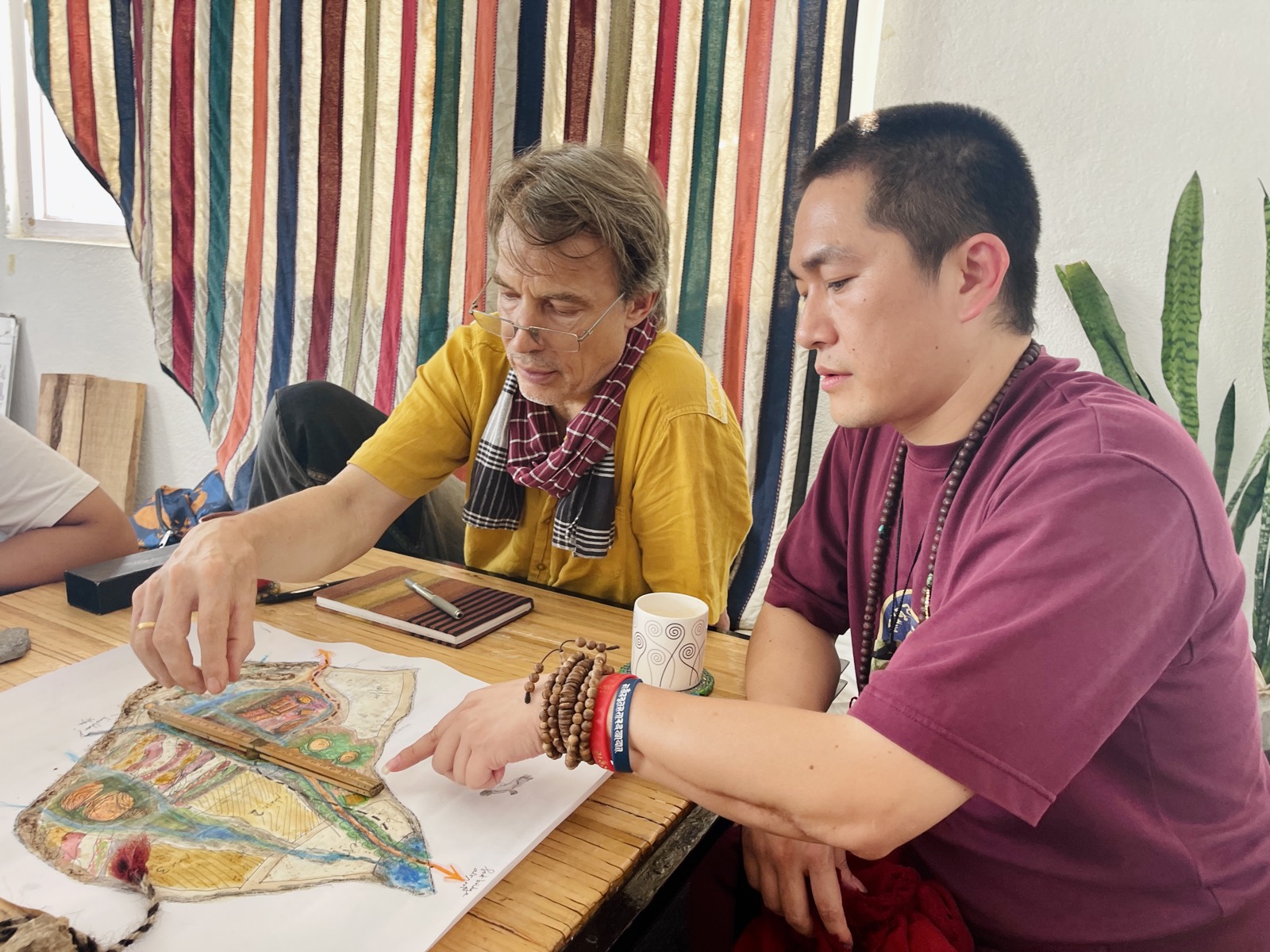 建築師與噶奇美多傑仁波切同時指向桌上的手繪園區規劃圖